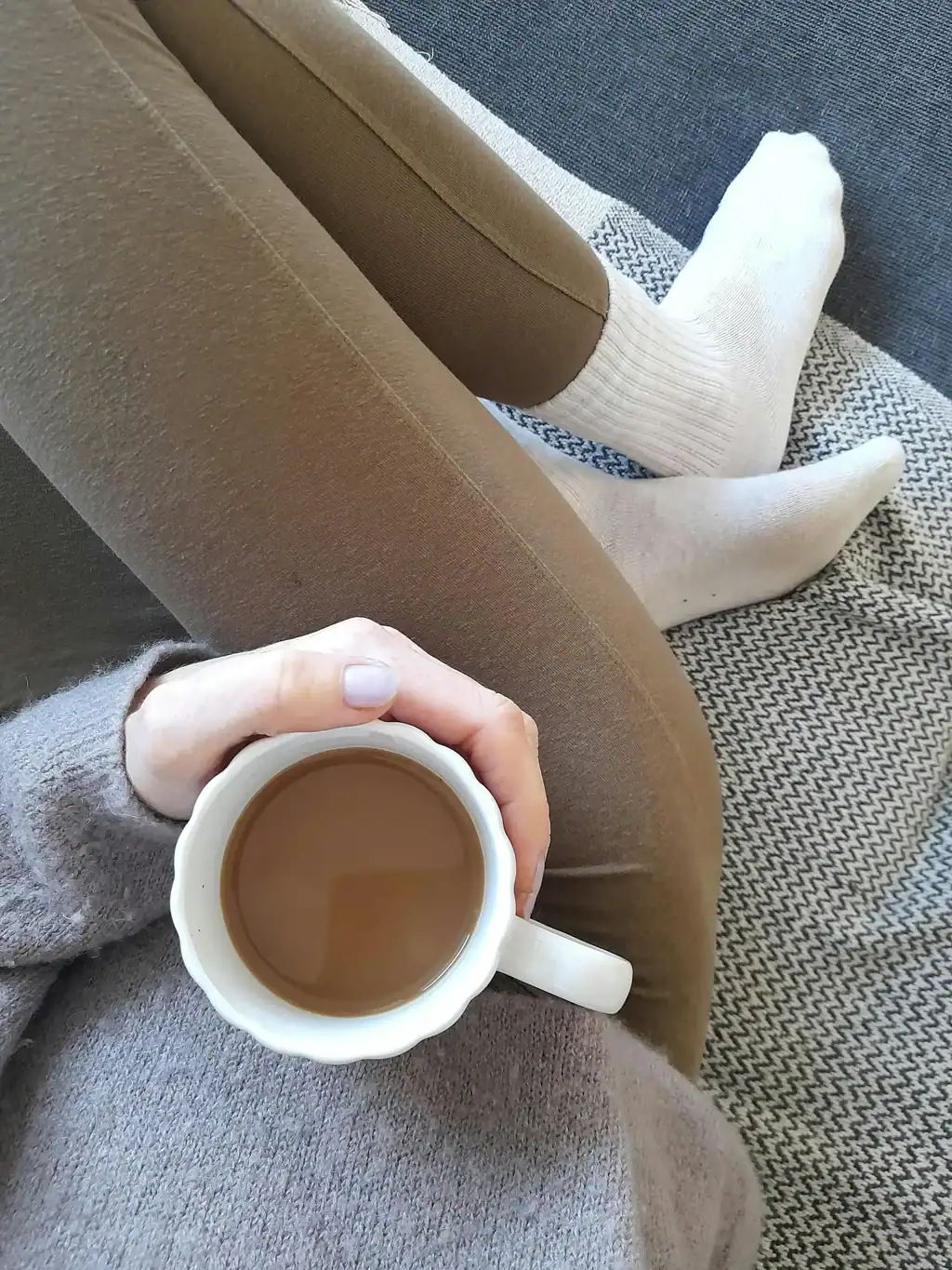 Woman relaxing on freshly cleaned herringbone upholstery sofa with coffee in Chicago living room