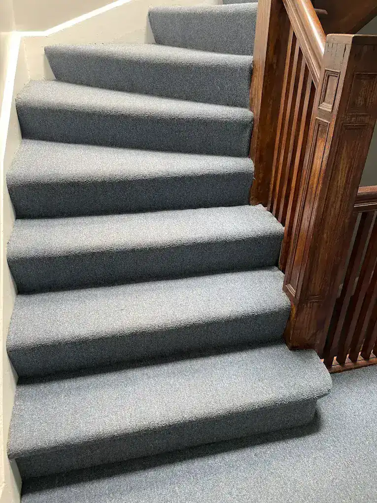 Clean gray stair carpet with a wood banister after cleaning by Carpet Cleaning Group, serving Lakeview, Chicago